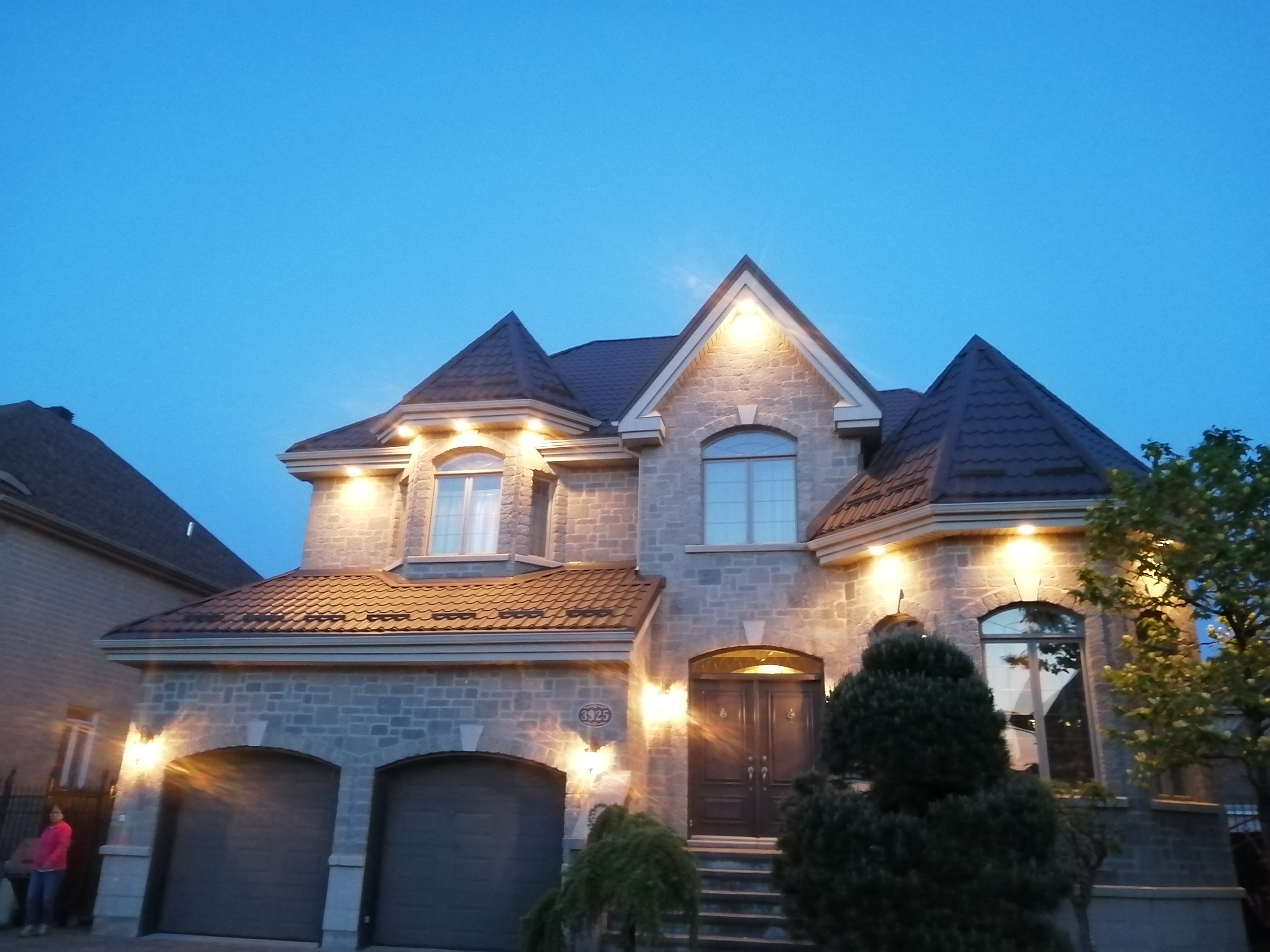 Completed metal shingle roof on a stone house at dusk