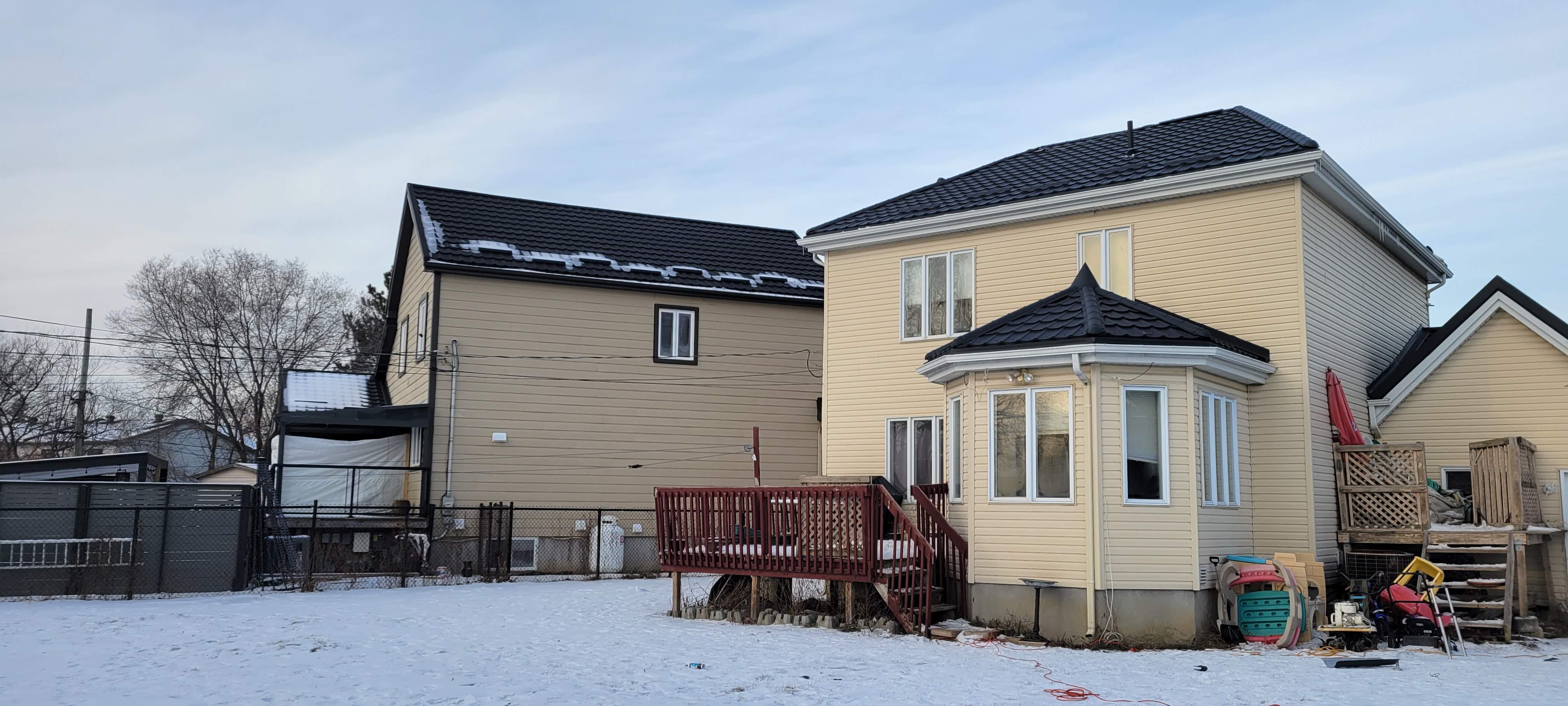 Two homes with new black metal shingle roofs in winter